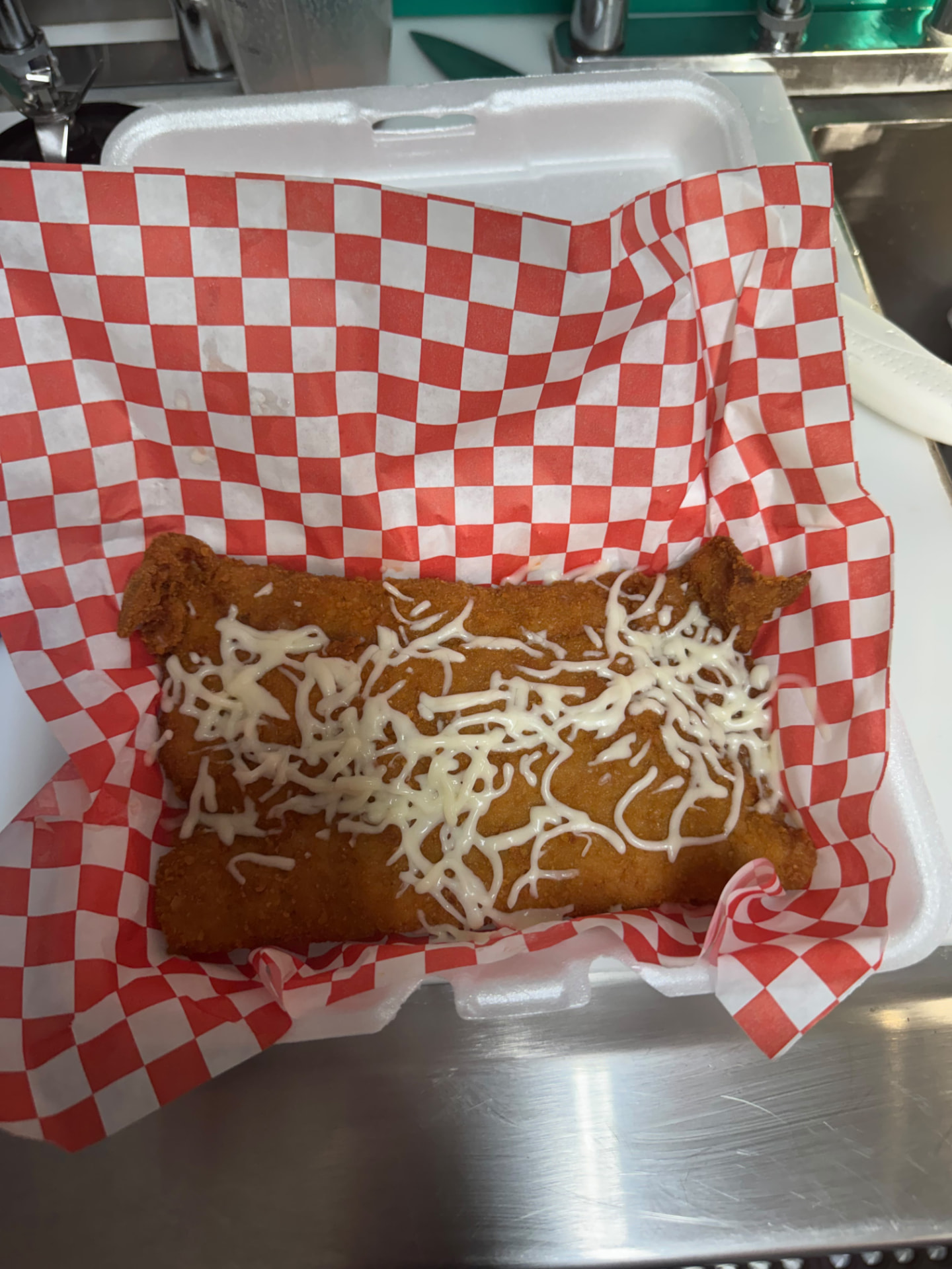 Completa de bistec uruguayo — breaded and fried Uruguayan steak with creamy sauce in a takeout container