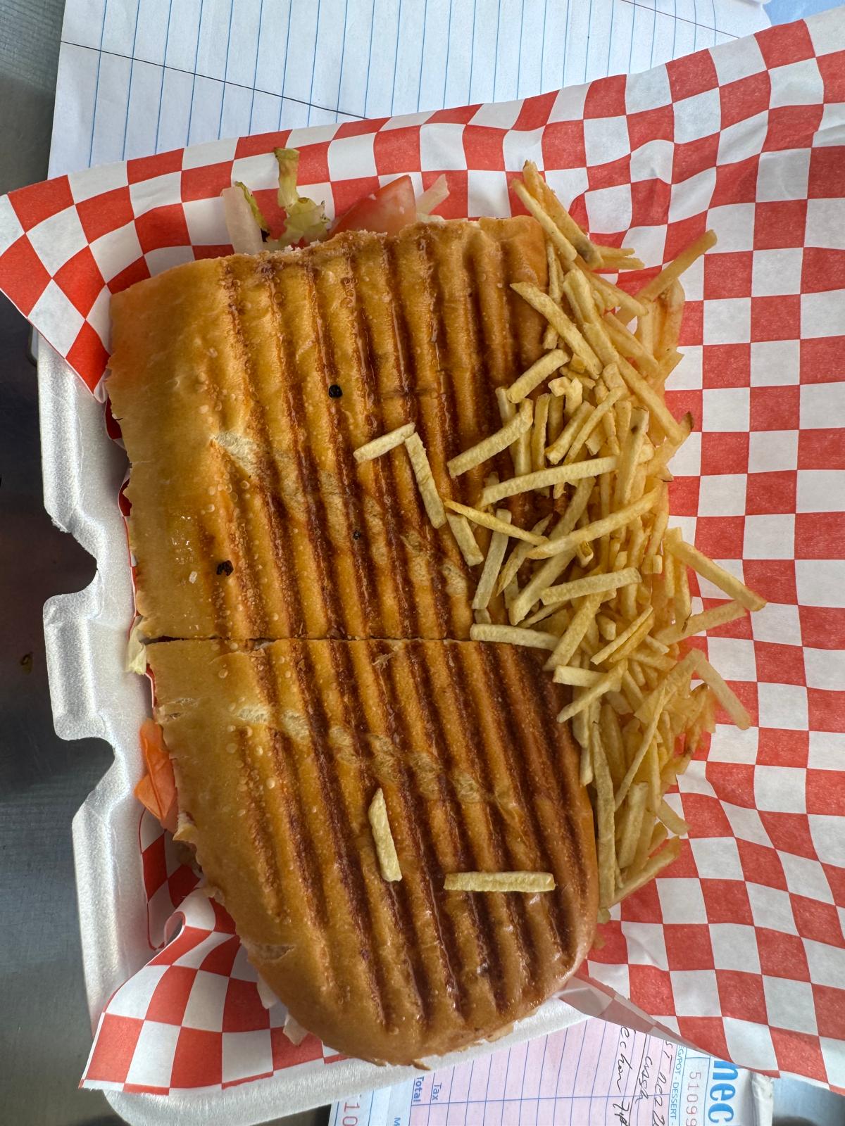 Pressed pork steak sandwich with shoestring fries in a takeout container