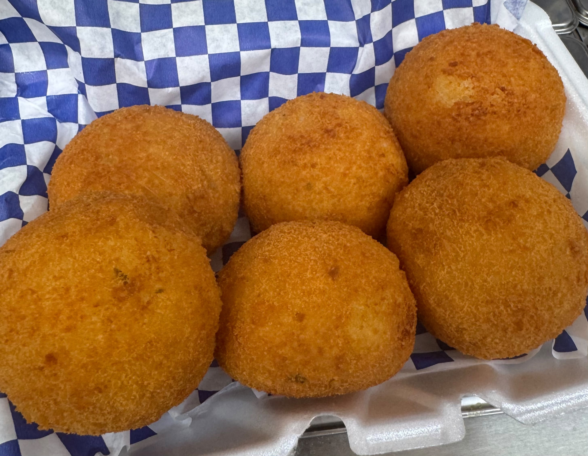 Golden crispy papas rellenas — stuffed fried potato croquetas in a takeout container
